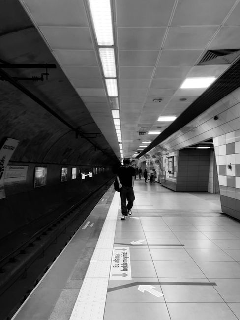 A clean and well-lit platform at Canonbury Station, showing smooth, polished tiles with clear directional markings and a white tactile strip along the edge. The underground tunnel features a curved ce